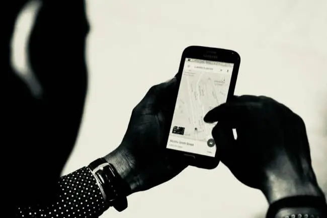Auto-generated description: A person is using a smartphone to navigate a map application.