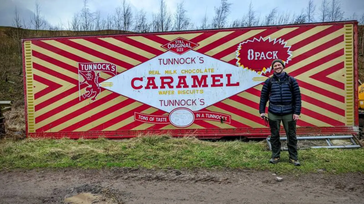 Aaron standing in front of a shipping container styled as a Tunnock's Caramel Wafer packet