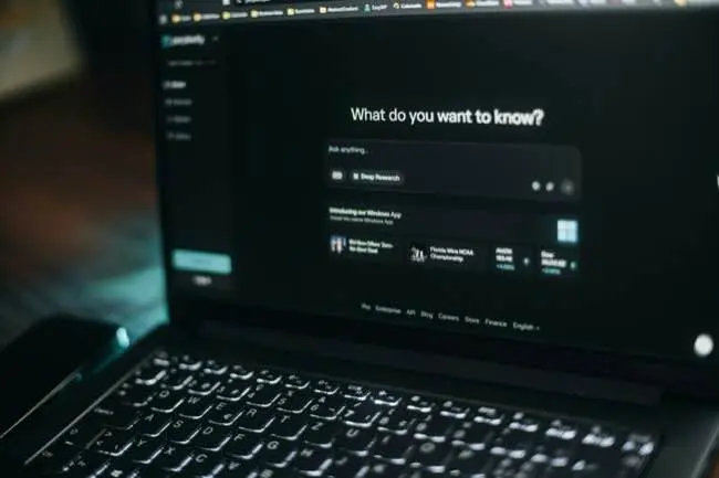 Auto-generated description: A laptop screen displays a webpage with a search box titled What do you want to know? above a keyboard.