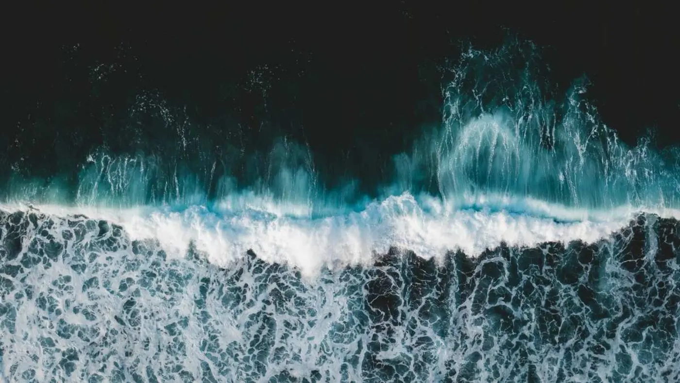 Aerial view of the white caps of waves crashing onto a beach