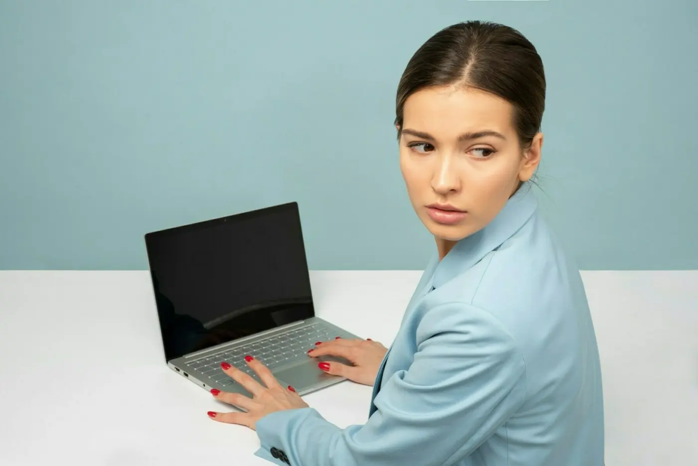 Woman using laptop looking anxiously over her shoulder