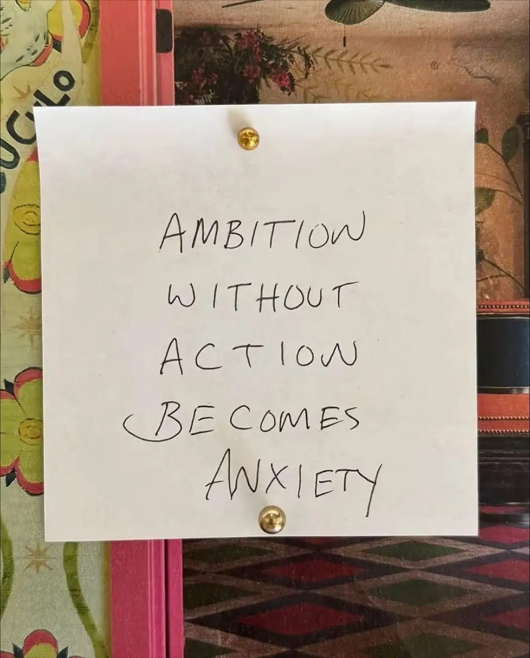 Auto-generated description: A note pinned to a wall reads, Ambition without action becomes anxiety.