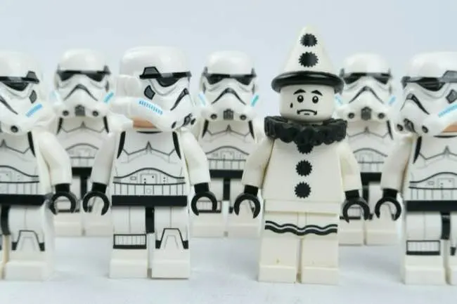 Auto-generated description: A group of LEGO stormtroopers surrounds a LEGO Pierrot clown figure.