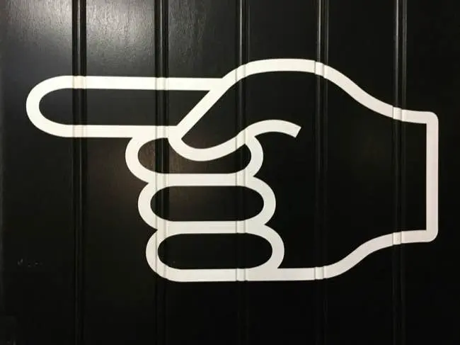 Black background with stylised white-outlined hand pointing to the left