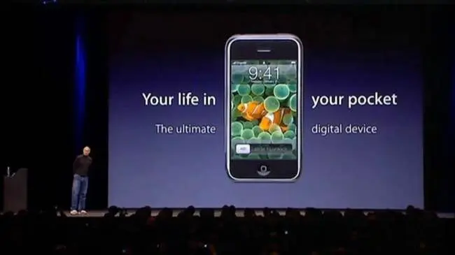 Steve Jobs standing next to a huge screen that shows the original iPhone. The words on the screen read "Your life in your pocket. The ultimate digital device."