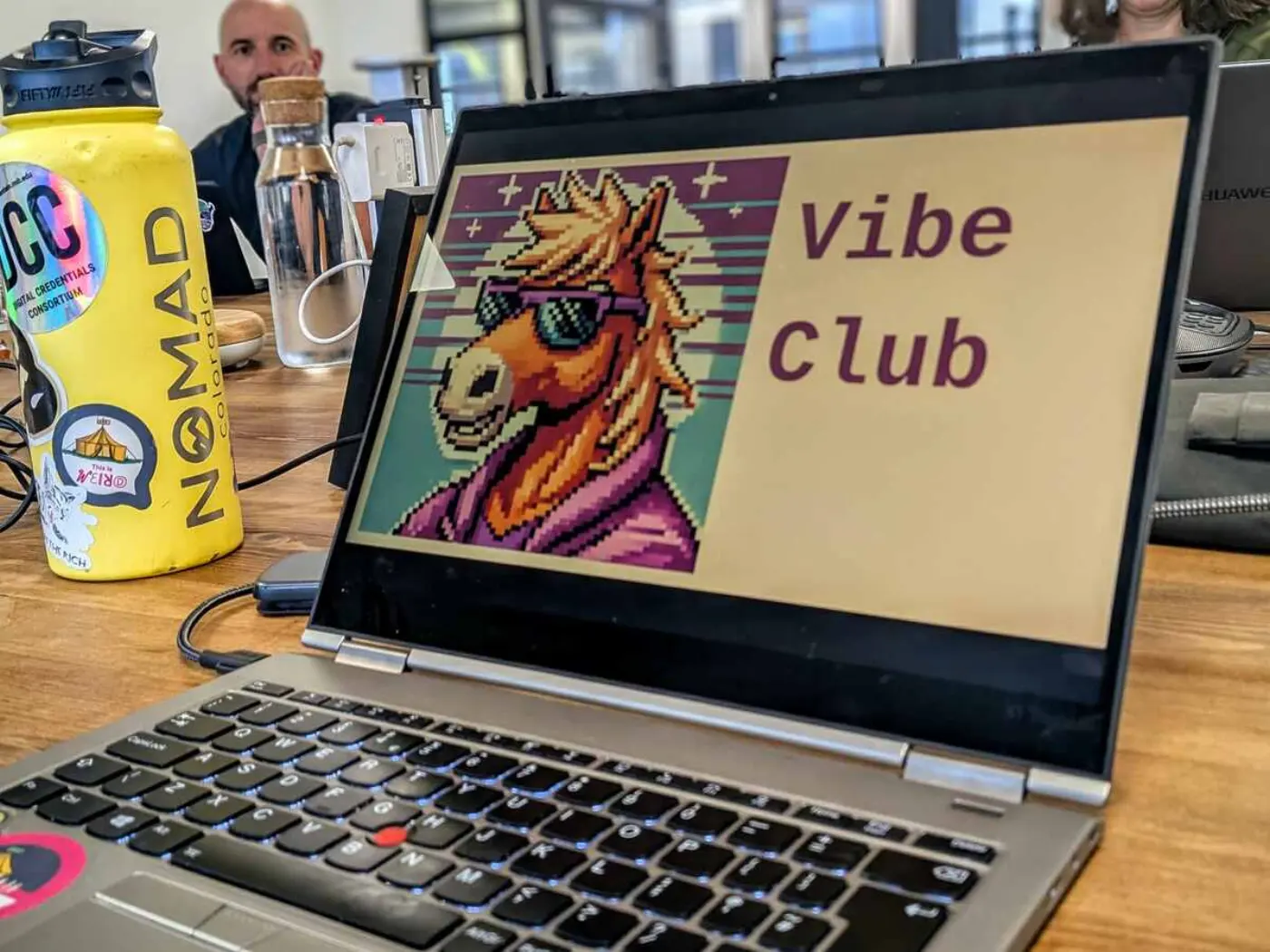 Photograph of laptop with the words 'Vibe Club' and an image of a pixellated horse wearing sunglasses