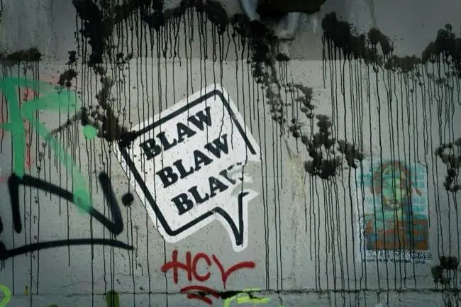Auto-generated description: A graffiti-covered wall features a speech bubble sticker saying BLAW BLAW BLAW and other colorful tags.