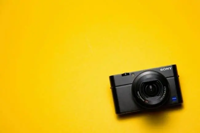 Auto-generated description: A black Sony camera is placed on a bright yellow background.