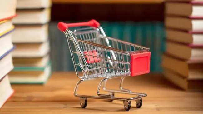 Tiny supermarket trolley amongst stacks of books
