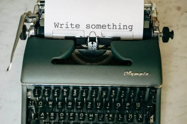 Green typewriter with paper that says WRITE SOMETHING