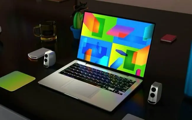 A sleek laptop on a modern desk displays colorful abstract art on its screen, surrounded by speakers, a mug, and a plant.