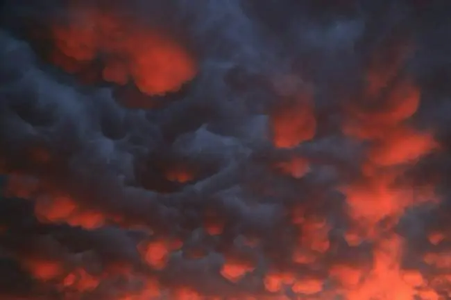 Auto-generated description: Dark, ominous clouds glow with a fiery red-orange hue, creating a dramatic sky scene.